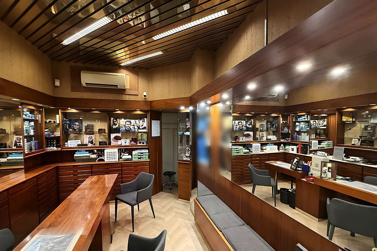 La sala di Ottica Parioli: vetrine illuminate, cassettiere in noce, soffitto a doghe e pavimento a spina di pesce
